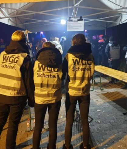 Drei Sicherheitskräfte der WGG Sicherheit in Warnwesten bei einer Abendveranstaltung